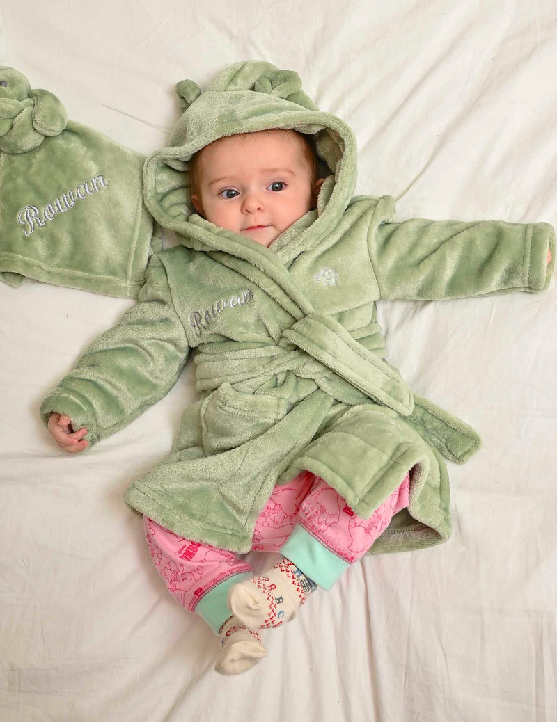  Babies personalised Green hooded dressing gown. Made from super soft material, it features an elephant embroidery to the chest as well as detailing pom pom ears and a hood. Make it extra special by adding a personalised touch.
